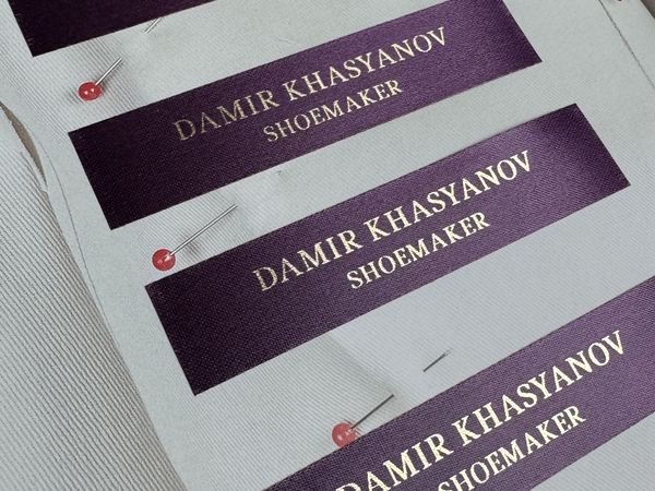 Горизонтальные пришивные бирки из премиального фиолетового сатина размером 70х15 мм с блестящей печатью золотом.